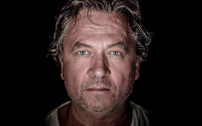 Portrett av Nils Petter Molvær med mørk bakgrunn.